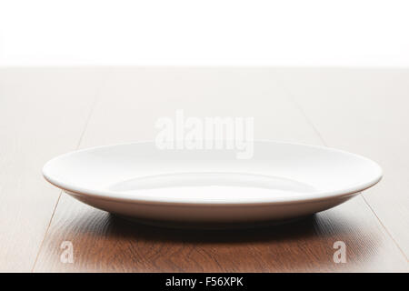 Leere weiße Keramik-Platte auf helles Licht braun Holztisch Hintergrund Stockfoto