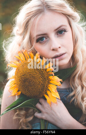Schöne junge Frau in einem Sonnenblumenfeld an goldene Stunde Stockfoto