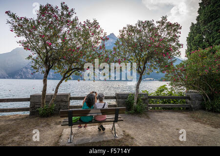 Junge Mädchen sitzen auf der Seepromenade in Riva del Garda, Gardasee, Lombardei, Italien Stockfoto