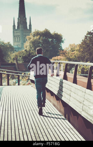Mann läuft über städtische Brücke mit Kirche im Hintergrund Stockfoto