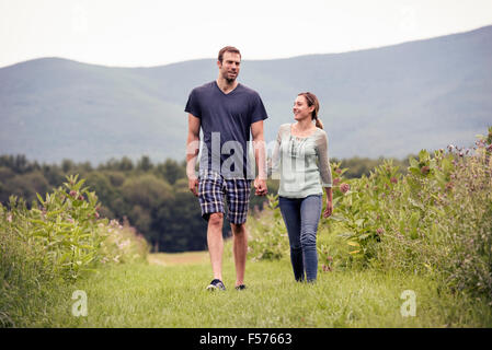 Ein paar, Mann und Frau durch eine Wiese, die Hand in Hand gehen. Stockfoto