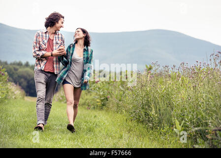 Ein paar, Mann und Frau zu Fuß durch eine Wiese auf dem Lande. Stockfoto