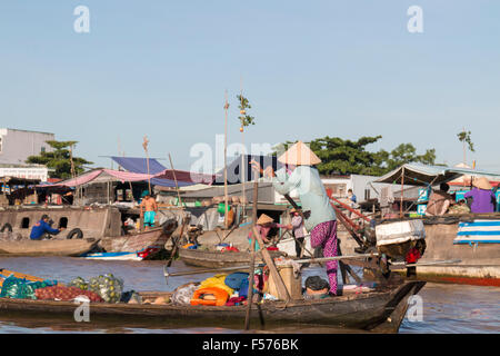 Vietnamesin mit einem Bein Rudern auf schwimmenden Märkte von Cai Rang zu kaufen verkaufen frisches Obst, den Futternapf von Vietnam Stockfoto