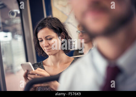 Eine Frau in einem Bus, blickte auf ihr Handy Stockfoto