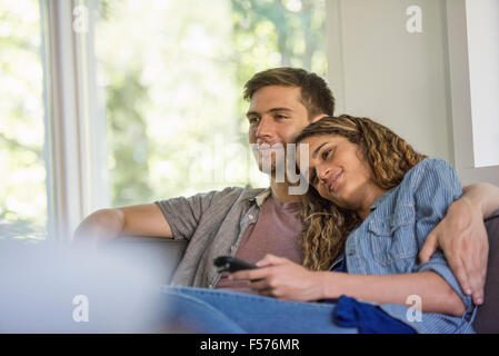 Ein paar, ein Mann und eine Frau sitzen nebeneinander lachen, auf einem Bildschirm. Stockfoto