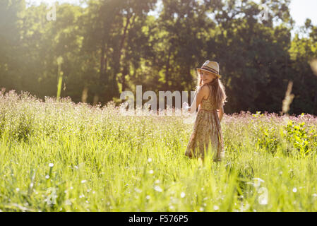 Ein junges Mädchen zu Fuß in ein Feld in der Sonne Stockfoto