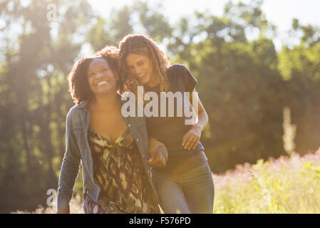 Zwei Frauen zu Fuß durch ein Feld reden und lachen. Stockfoto