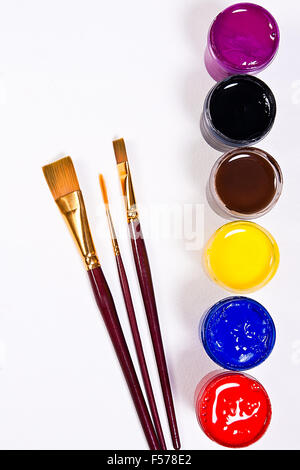 Flaschen mit Gouache Farben und verschiedene Arten von Bürsten für künstlerische Gemälde auf dem weißen Hintergrund. Stockfoto