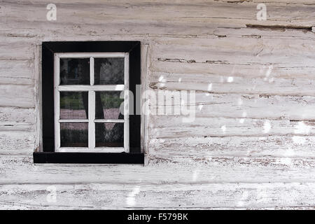 Vintage-Hintergrundtextur. Holzwand mit Fenster der alten Landhaus aus Protokollen mit Lehm bedeckt als eine Hintergrundtextur. Stockfoto