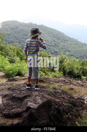 Es ist ein Foto von einem kleinen Jungen die Skyline oder Landschaft mit seinem Fernglas beobachten. Er ist in den Wald oder die Natur wandern. Stockfoto