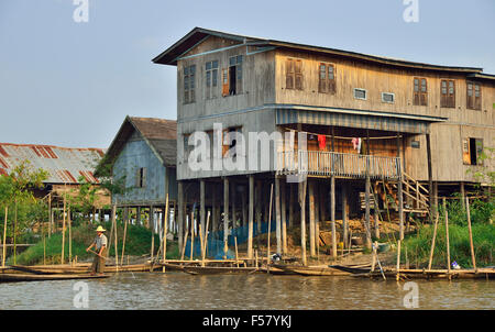 Ethnische Minderheit Intha Mann paddeln Boot außerhalb Pfahlbauten am Inle See, Shan Staat, Myanmar (Burma), Südostasien Stockfoto