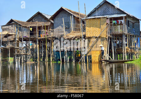 Ethnische Minderheit Intha Woman in einem kleinen Boot vor dem Pfahlhaus auf Inle Lake, Shan State, Myanmar, (ehemals Birma), Südostasien Stockfoto