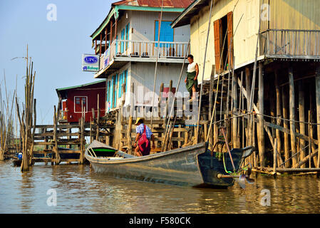 Angehörige ethnischer Minderheiten, die in ein Langboot vor ihrem Pfahlhaus am Inle Lake, Shan State, Myanmar, ehemals Birma, einsteigen Stockfoto