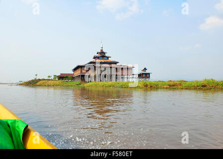 Touristen Reisen in einem Long-tailed motorisierten Boot (unten links) vorbei an einem Tempel auf einer Insel in einem Zufluss zum Inle See, Stockfoto