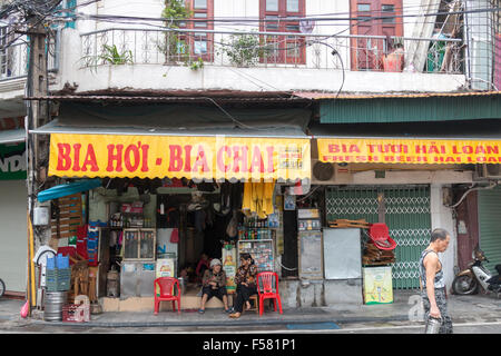 Hanoi old Quarter zwei Damen sitzen außerhalb ihrer Café und ältere Mann zu Fuß durch, Vietnam. Bia Hoi an ist die lokale billiges Bier. Stockfoto