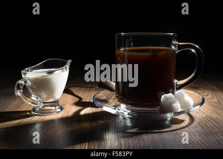 Kaffee in eine transparente Becher, Milch, Löffel und Zucker Stockfoto