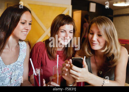 Freunde sprechen im Café und betrachten der Fotos auf Smartphone Stockfoto