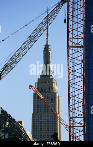 Baukräne auf einer Baustelle auf der Westseite von Manhattan mit Empire State Building in New York City USA Hintergrund Stockfoto