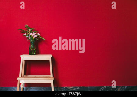 schlichtes Design, Interieur, Blumen in Vase auf der roten Wand Hintergrund Stockfoto