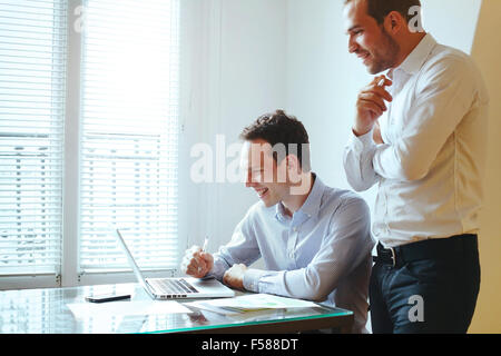 zwei junge Geschäftsleute, die lachend vor computer Stockfoto
