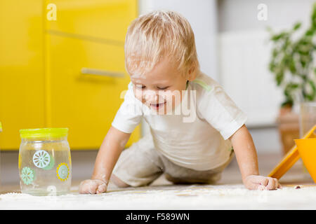 Kleiner Junge spielt mit Geschirr und Lebensmittel in der Küche Stockfoto