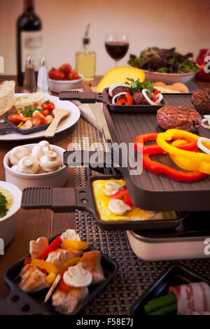 Schweizer Raclette oder die niederländische Variante "Gourmetten". Eine Tabelle mit Zutaten für ein Gericht, die in der Regel auf Celebrato serviert wird gefüllt Stockfoto