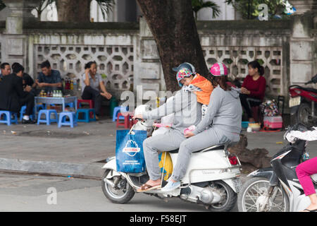 Ein junges Mädchen, das auf einem Motorrad steht, zwischen Mutter und Vater in Hanoi, Vietnam, Asien Stockfoto