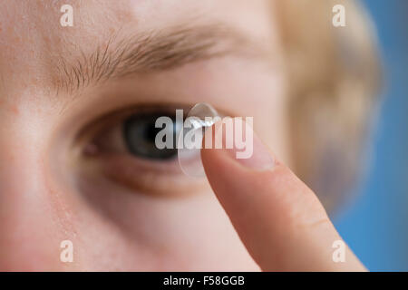 Ein junger Mann balanciert eine Kontaktlinse ist Zeigefinger. Stockfoto