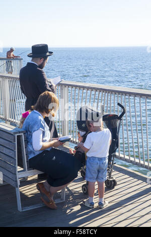 Orthodoxen chassidischen jüdischen Familie beten während der hohen Feiertage auf dem Pier auf Coney Island, Brooklyn, New York. Stockfoto