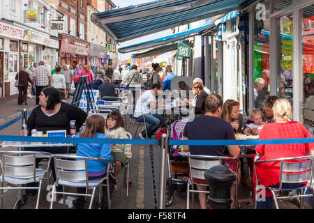 Menschen außerhalb eines Cafe Essen auf der Straße, Skegness, England, UK sitzen Stockfoto