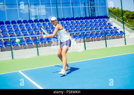 Schöne weibliche Tennisspieler in Aktion, schlagen eine Vorhand Stockfoto