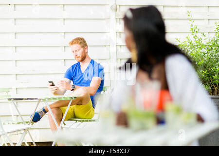 Schöne schwarze Frau mit Blick auf ein gut aussehender Mann in einem Café im freien Stockfoto