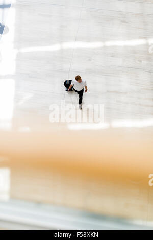Gut aussehend Geschäft hält einen Wagen und zu Fuß in einem modernen Gebäude, die von oben gesehen Stockfoto