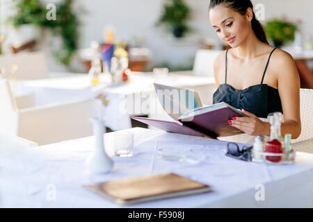 Schöne Frau-Menü im Restaurant bestellen und entscheiden, was zu essen Stockfoto