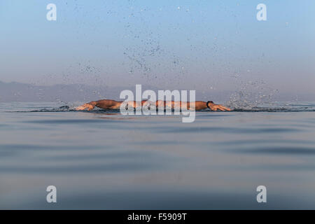 Muskulösen jungen Mann schwimmen Schmetterling im Meerwasser Stockfoto