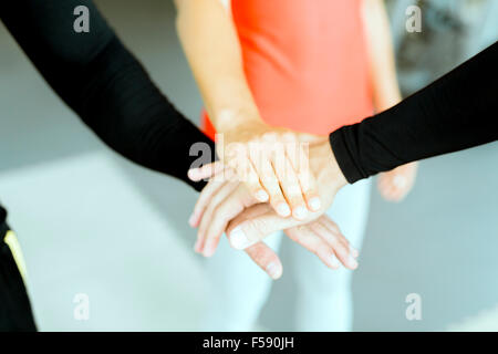 Drei Hände zwischen Sportlern als Zeichen der Zusammenarbeit und Einheit übereinander gelegt. Stockfoto