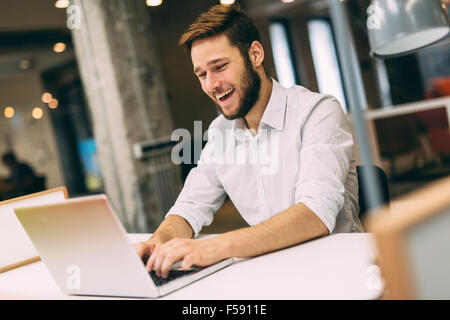 Gut aussehend männlichen Arbeit in einem Büro und tippen auf einen Laptop während lächelnd Stockfoto