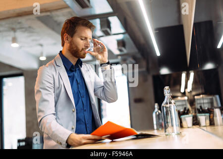 Geschäftsmann, Wasser zu trinken und Zeitung lesen, während der Pause Stockfoto