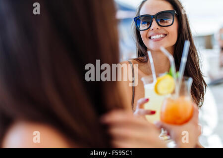 Fröhliche Freundinnen im Sommer Cocktails trinken und lächelnd Stockfoto