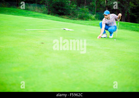 Golfspieler, die Kugel auf dem Putting-Green vor dem Anheben des Balls markieren Stockfoto