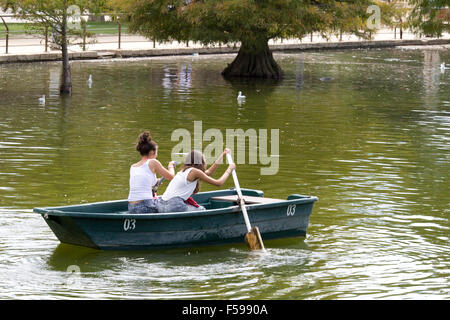 Zwei Mädchen, die versuchen, ein Paddelboot hinunter die Serpentine in London zu rudern Stockfoto