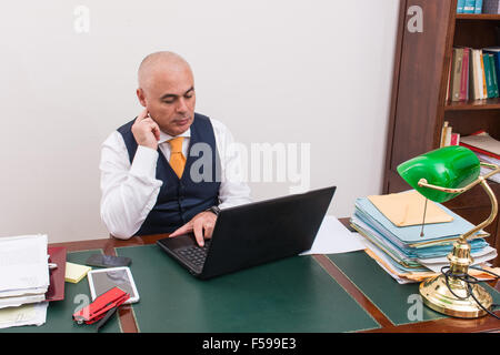 Unternehmer nutzt Laptop, am Schreibtisch bei der Arbeit, in seiner professionellen Studio, mit Händen und Fingern. Stockfoto