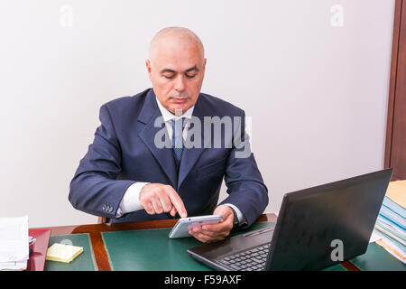 Der Mann am Schreibtisch, betrachten Sie Ihre i Pad/Tablet, in seinem Büro. Stockfoto