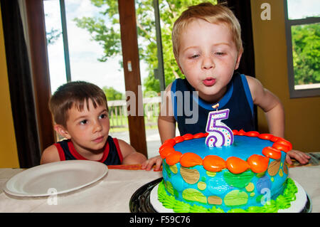 Boy bläst Geburtstag Kerze auf Kuchen Stockfoto