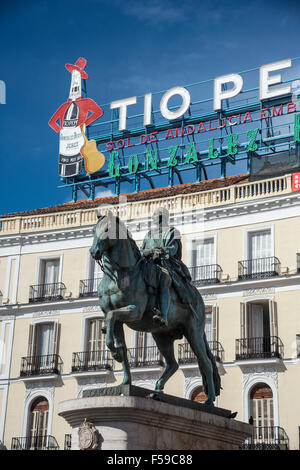 Das berühmte Tio Pepe Reklameschild erhebt sich über eine Statue von König Carlos III, an der Puerta del Sol, Madrid, Spanien. Stockfoto