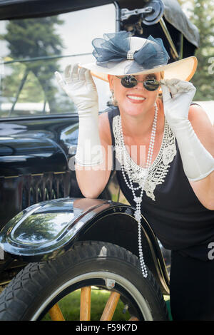 Attraktive Frau in zwanziger Jahre Outfit in der Nähe von antiken Automobile Stockfoto