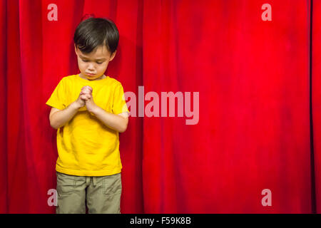 Gemischte Rassen junge mit betenden Händen vor roten Vorhang. Stockfoto