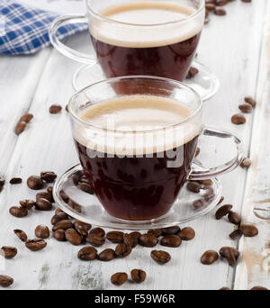 Zwei Glas Kaffeetassen und Bohnen auf hölzernen Hintergrund. Selektiven Fokus Stockfoto