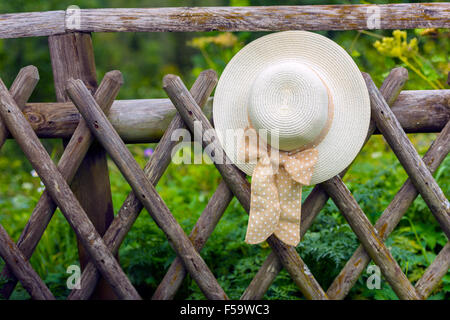 Weibliche Sommerhut hängen rustikale Holzzaun. Kleinen Griff gedreht Stockfoto