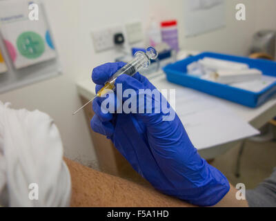 Ein Mann rollt seinen Ärmel um eine Grippeimpfung zum Schutz vor Grippe über Winter haben Stockfoto